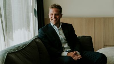 Eirik Rise sitter i en grønn sofa og smiler til kameraet