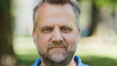 Mann med skjegg i blå piquetskjorte ute om sommeren 