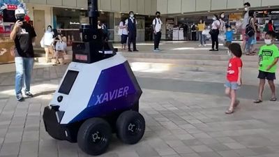 Robot på hjul ute i gate, med folk som ser på.