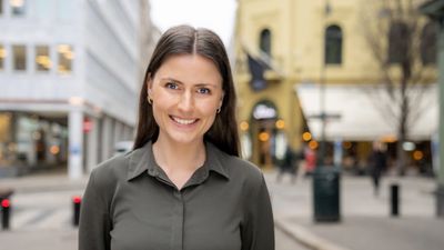 En smilende kvinne i grå skjorte i gatemiljø i Oslo