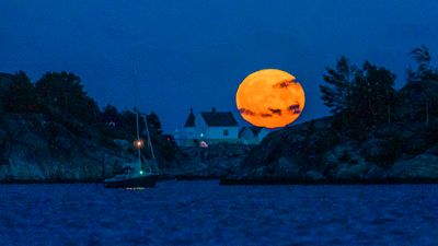 Månen stiger opp over Saltholmen utenfor Lillesand, seilbåt i forgrunnen.