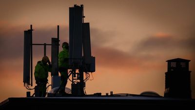 Bildet viser teknikere som driver vedlikehold på en takmontert basestasjon.