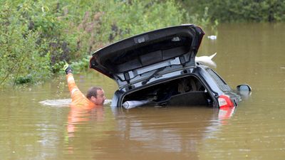 Bil er tatt av flommen, redningsmann har svømt bort til den.