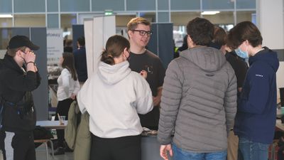 En gruppe studenter snakker sammen inne i et rom fult av rollups