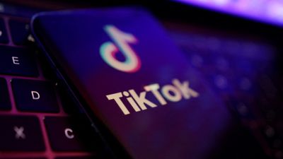Mobil med Tiktok-logo som ligger på tastaturet til en laptop.