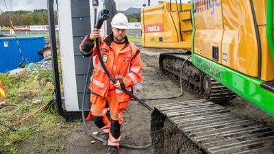 Elektrisk anleggsplass. Anleggsmaskinfører Thomas Tyssøy holder en ladekabel som skal kobles til en elektrisk gravemaskin.