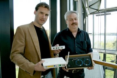 <p>Prosjektleder Jan Helge H&oslash;gvoll og leder for optiske nett, &Oslash;yvind Arntzen viser fram Telenors kundeenhet, p&aring; fiberspr&aring;ket omtalt som en ONT - optical network termination - i dagligtale gjerne omtalt som et \"fibermodem\", samt enheten som skal levere tjenestene - en \"residential gateway\".</p>