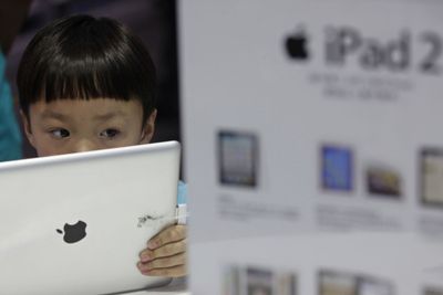 En kinesisk gutt ser på Apples iPad i en butikk i byen Wuhan. Selv om iPad ikke er offisielt til salgs i Kina er etterspørselen og interessen på det grå markedet stor.