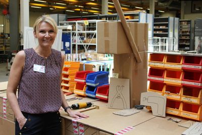 Heidi Svensen foran en arbeidsstasjon i kartong – som har dannet grunnlaget for bestilling av ny skreddersydd stasjon.