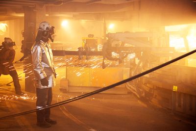 Arbeidere i flammehemmende drakter renser tappekanalene på den ombygde og miljøvennlige smelteovnen på Elkem Salten.