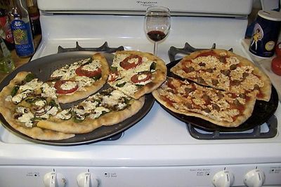  Slik forklarer Googles nettverk dette bildet: Two pizzas sitting on top of a stove top oven. 