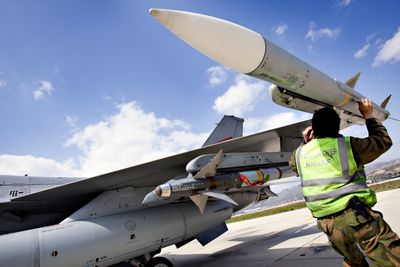 En militær tekniker kontrollerer et AIM-120B Amraam-missil på vingespissen på et norsk F-16 på flybasen Souda på Kreta i forbindelse med operasjon Odyssey Dawn for snart to år siden. Lenger inn på vingen et AIM-9 Sidewinder kortholdsmissil som Nammo også lager motoren til.  Foto: Lars Magne Hovtun/Forsvarets mediesenter 