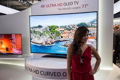 Verdens største OLED: LG overrasket alle og trakk sløret av verdens største OLED-TV. 77 tommer med kurvet skjerm og 4K-oppløsning. Selvfølgelig med smilende vertinne. 
