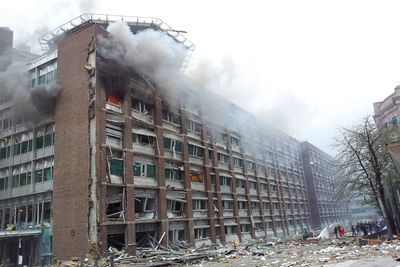 KNUST: Regjeringsbygg 4 (R4) har fått en nærmest ugjenkjennelig fasade etter eksplosjonen. Helikopterdekket på taket skimtes bak røyken fra en brann i en av de øverste etasjene.