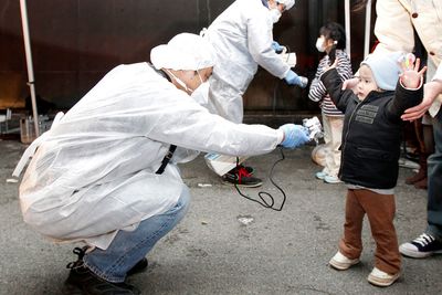 SJEKKES: Tjenestemenn i beskyttelsesutstyr leter etter spor av stråling på barn fra det evakuerte området nær kjernekraftverket Fukushima Daini i Koriyama.