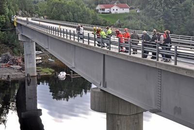 På denne siden av brua skal det monteres en gangbane. Bildet er tatt i august i fjor. De som står på brua, følger med på forberedelsene til å rive hengebrua som sto ved siden av.