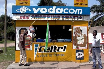 To menn står utenfor en kiosk som selger mobiltelefonkort i Kongos hovedstad Kinshasa. Mobiltelefonrevolusjonen i Afrika har enorme positive ringvirkninger for kontinentet både økonomisk, sosialt og politisk.