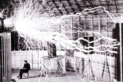 Nikola Tesla i laboratoriet i Colorado Springs, desember 1899. Bildet er dobbeleksponert - de elektriske strålene er tatt i et mørkt rom, mens Tesla og rommet er eksponert i etterkant.  