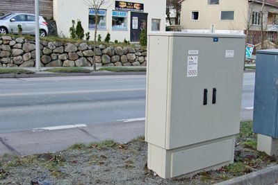 Nytt og gammelt telleskap. Det nye er egentlig to skap. Det ene er for sterkstrøm. Det kan bare autoriserte elektrikere åpne. Det andre er for svakstrøm. Det kan alle med nøkkel hente trafikkinformasjon fra. Sporene i asfalten er synlige til venstre på bildet. (Foto: )