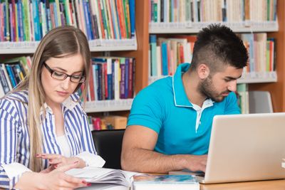 In The Library - Handsome Two College Students With Laptop And Books Working In A High School - University Library - Shallow Depth Of Field