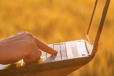 Businessman is on a field of ripe wheat and holds a laptop in his hands. The concept of the agricultural business.