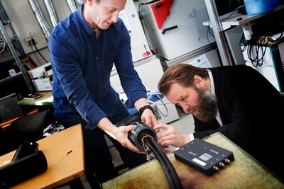 Sigbjørn Kolberg, forsker ved Avdelingen for smarte sensorsystemer ved Sintef Digital og Morten Huseby, daglig leder i Wirescan, monterer det nyutviklede målesystemet på kabelen i kjelleren hos Sintef.
