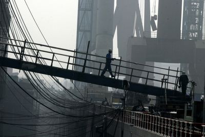 En kinesisk verftsarbeider går over broen som leder til et fraktskip for råolje på Dalian New Shipbuilding Heavy Industry Co. Ltd i Dalian i nordøstlige Kina.