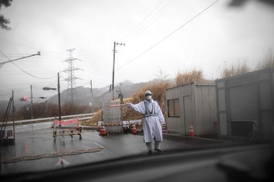 En vakt gestikuklerer ved sjekkpunktet på vei inn i en av forstadene til Fukushima. Bildet er tatt i mars 2018.