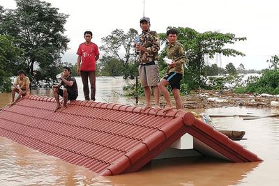 Landsbyboere har søkt tilflukt på et hustak i Attapeu distriktet, sør i Laos, tirsdag 24. juli, 2018.