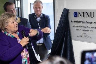 Erna Solberg sto for den offisielle åpningen av Norwegian cyber range. Etter å ha avduket skiltet tok hun seg tid til å brette duken pent sammen før hun overleverte den til instituttlederen.