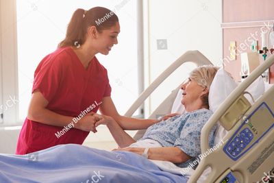 stock-photo-nurse-talking-to-senior-female-patient-in-hospital-bed-361341161-1
