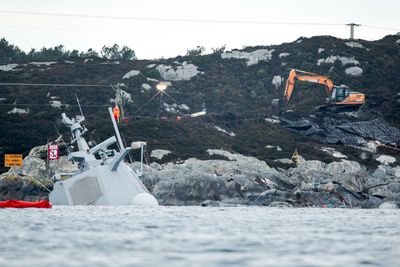 Det pågår arbeider i land rett ved der fregatten KNM Helge Ingstad ligger. En gravemaskin legger på plass sprengmatter oppå fjellet og det er trukket gule tau ut til akterenden av havaristen som så vidt stikker opp av vannet.
Foto: Tore Meek / NTB scanpix