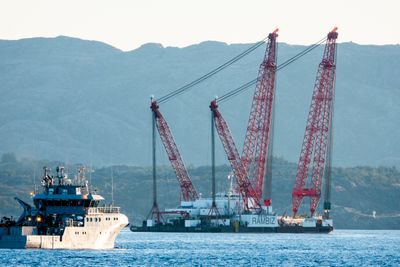 Kranbåten Rambiz passerer et skip fra Kystvakta på sin vei innover Hjeltefjorden hvor fregatten Helge Ingstad forliste. Sammen med en annen kranbåt skal Rambiz heve fregatten.