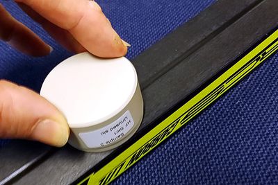 Testing: Ved å dytte en teipbit festet til en prøveholder mot skisålen, kan man etter noen sekunder i et spektroskop se om skien er glidet med fluor. Foto: NILU

 