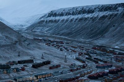 Longyearbyen med Sukkertoppen til venstre. Store snømengder raste ned fra fjellet i desember 2015, og knuste ti hus i området midt på bildet. Nede til venstre bygges nye, skredsikre boliger.