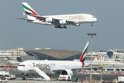 Et A380-800 går inn for landing i Dubai, der det står et B777-300ER parkert.