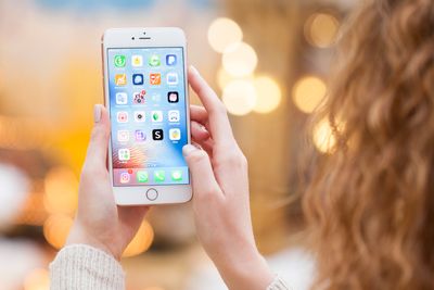 MOSCOW, RUSSIA - January 21TH 2018: a hand holding a iPhone 7 mini which displays the installation screen of the apps. An illustrative editorial image on an interior background.