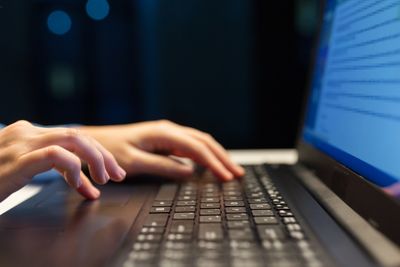 business, education and technology concept - close up of female hands with laptop typing at night