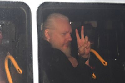 Julian Assange gjør en gest fra bilen hvor han føres bort etter pågripelsen torsdag. 