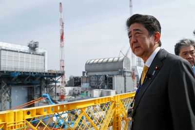 Japans statsminister Shinzo Abe besøkte atomkraftverket i Okuma søndag. Her står Abe utenfor reaktor nummer 2 (til venstre) og nummer 3 (til høyre).