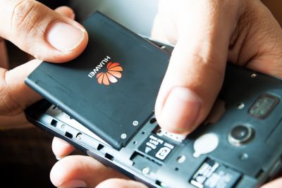 BANGKOK, THAILAND - May 28, 2019 : Man hands pulling battery of Huawei phone, stop using. USA and China trade war. Editorial. Huawei banned 