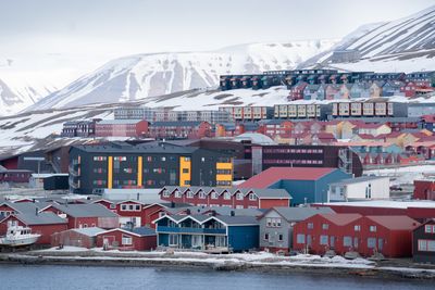 Bygningene i Longyearbyen synker mer enn de målte bygningene andre steder på Svalbard. UNIS' relativt nye gjestehus (grå og gul bygning midt i bildet) sank i fjor med 8 millimeter på flere av målepunktene.