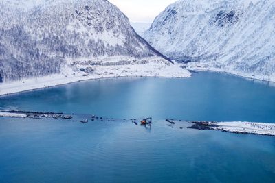 Gravemaskin «på fisketur» under arbeid på fyllingene på flo sjø sist vinter. Kryssingen av Sifjord på Senja skjer helt inne i fjordbunnen, for å unngå en rasfarlig veibit på sørsiden av fjorden.     