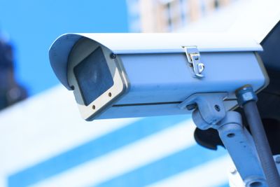 Camera system guarding blue skyscraper office building with sky above