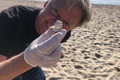 Henrik Fisker plukker havsøppel på stranden i Malibu. Hans nye elbil skal blant annet gjenbruke gamle fiskegarn.