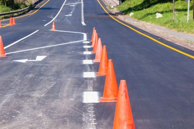 Road painting lines on new asphalt surface with orange markers