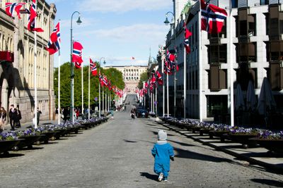 En liten gutt har stor boltreplass på Oslos paradegate Karl Johan. En annerledes 17.mai feiring på grunn av korona-pandemien sørger for en nesten folketom Karl Johansgate som vanligvis ville vært fylt opp med tusenvis av mennesker i barnetog på vei mot Slottet.