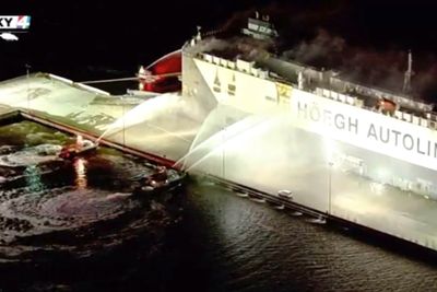 In this image made from aerial video taken on June 4, 2020, firefighters spray a cargo ship with water, in Jacksonville, Florida. Authorities say nine firefighters responding to a fire aboard a ship in Florida have been hospitalized after the ship exploded. The ship, a Norwegian vessel called Hoegh Xiamen was carrying old and used cars and had been scheduled to leave Jacksonville, First Coast News reported.  (WJXT via AP)