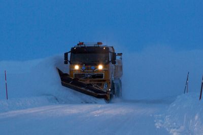 Snøbrøyting i blåtimen. Brøytebil på riksvei 890 Kongsfjordfjellet. Tana kommune. Finnmark.Snow Plough in the blue hour on a mountain road at Finnmark County. Northern Norway.