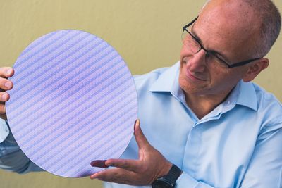 Selv Intel har begynt å tjenesteutsette deler av mikrobrikkeproduksjonen til andre deler av verden. Nå ønsker mange av brikkeprodusentene at utviklingen snus og at bransjen at utviklingen snus oig at det legges til rette for at mer halvproduksjon gjøres i USA. På bildet viser en Intel-ansatt fram en silisiumskive («wafer») med 8. generasjon Intel Core-prosessorer.